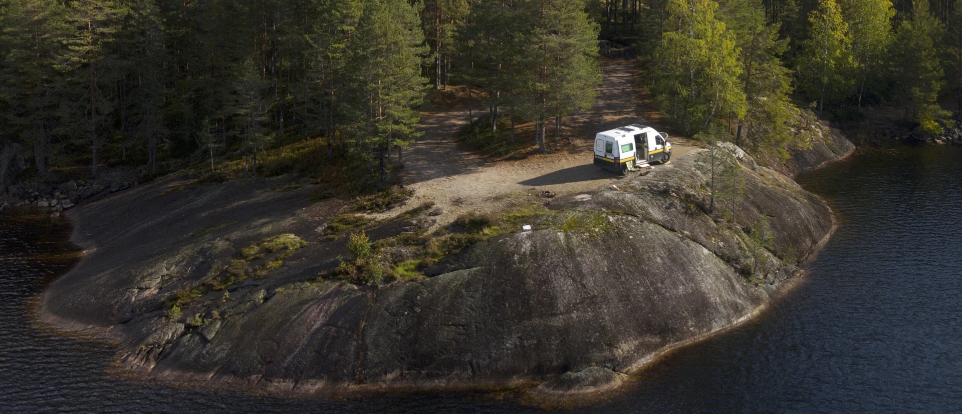 Campervan an einem See mitten im Wald